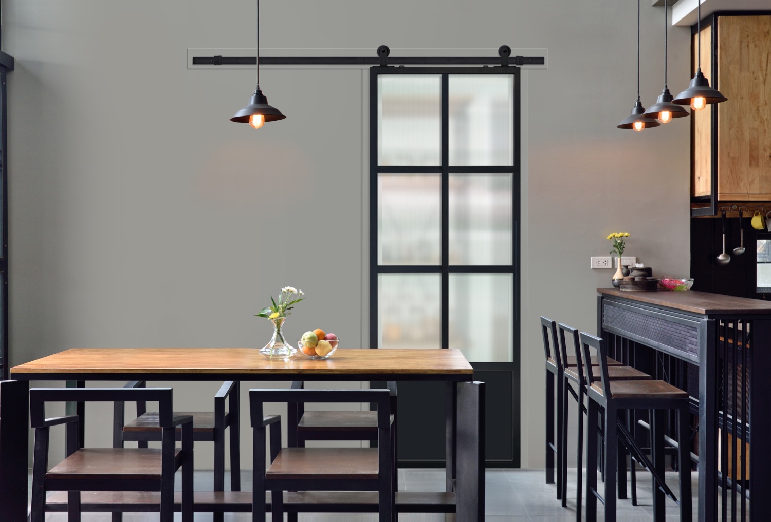 Black Modern French 6 Lite barn door with cloud glass closing off a pantry beside a dining table and kitchen bar
